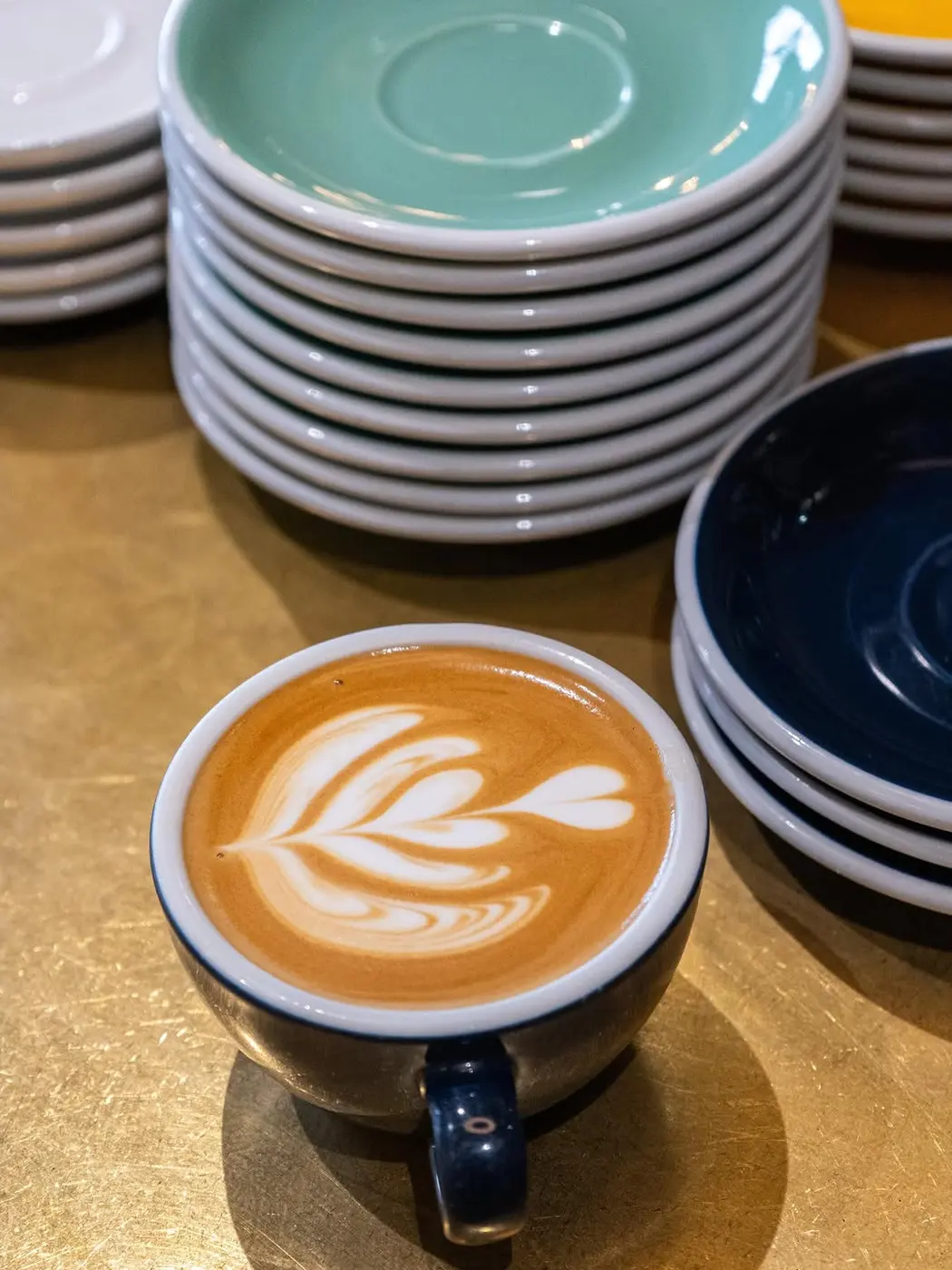 A flat white with latte art, resting on a stack of saucers