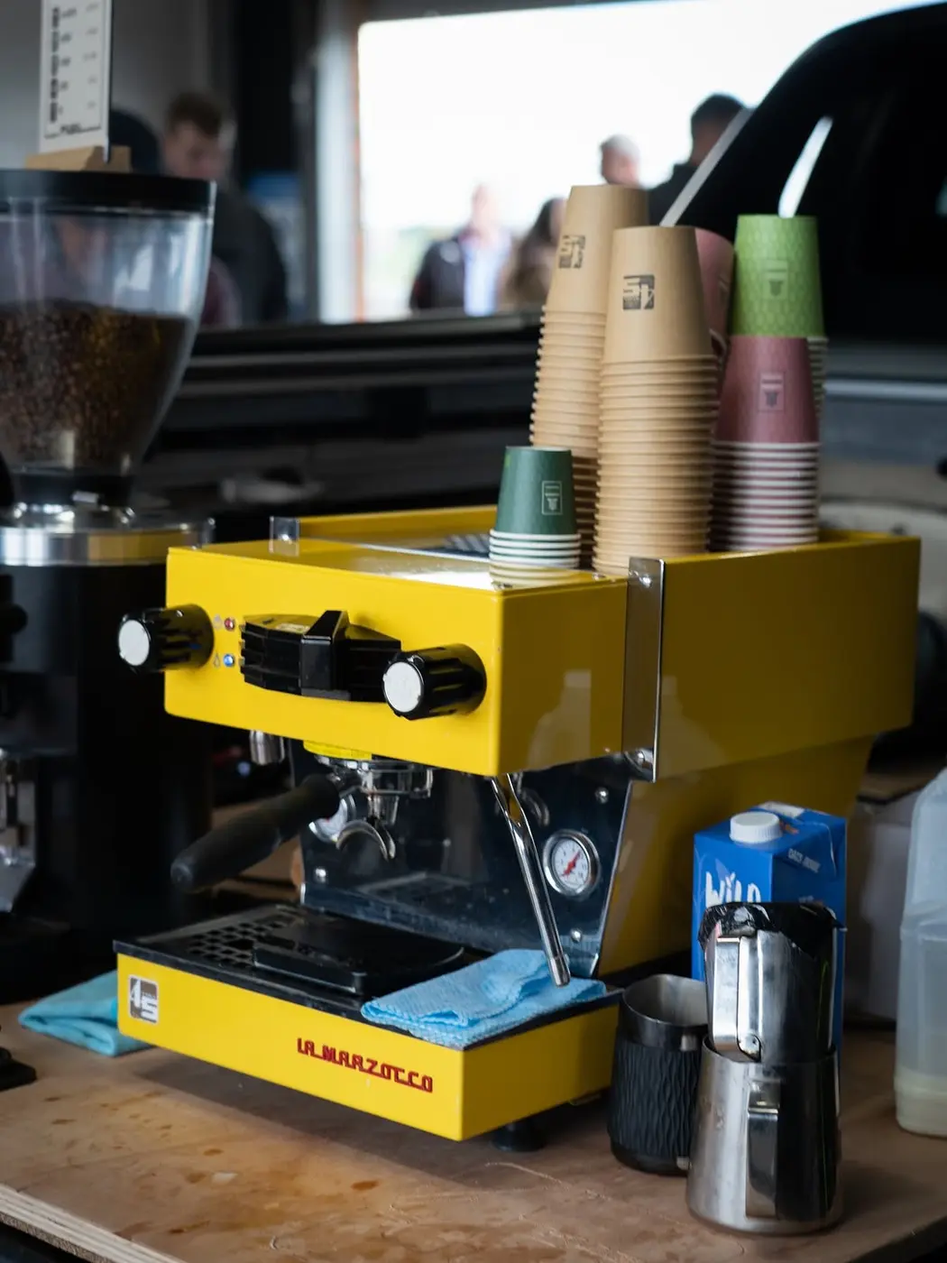 Takeaway cups stacked on a yellow La Marzocco espresso machine at 45 Fuel