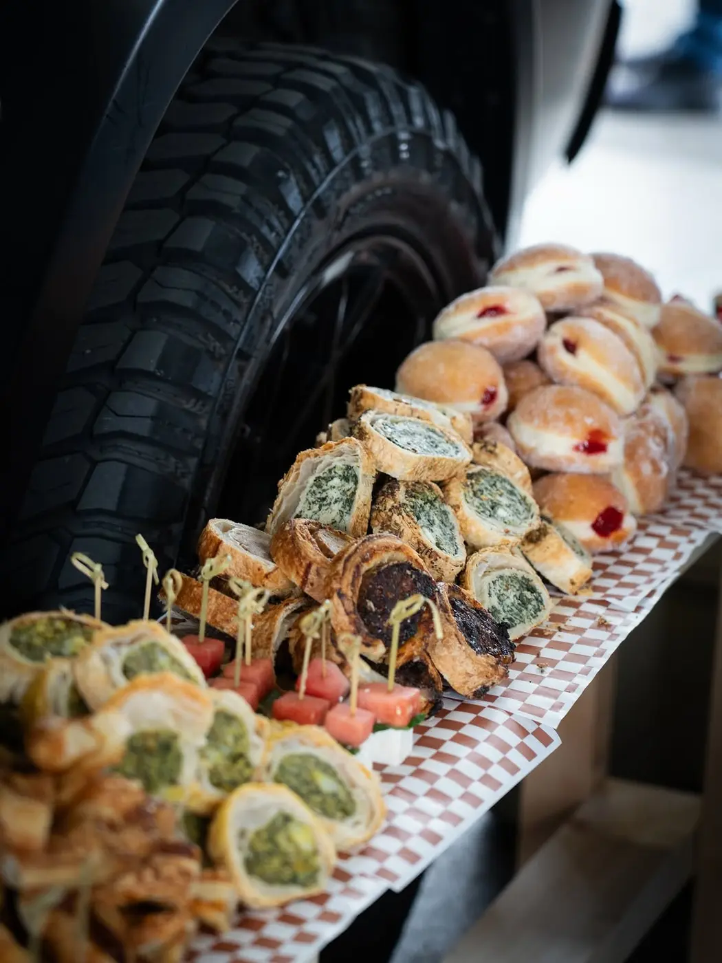 Pastry rolls, doughnuts and bites laid out on a tray beside a chunky off-road tyre