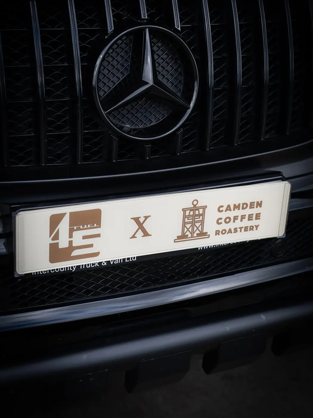 A 45 Fuel and Camden Coffee Roastery plate mounted on the grille of a black Mercedes AMG